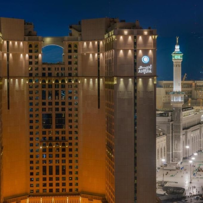 Anjum Hotel towers illuminated at night beside the Makkah skyline